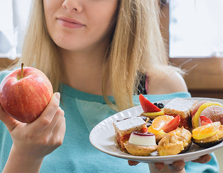 woman choosing healthy apple over dessert junk swap
