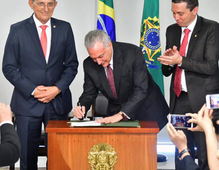 The photo, taken on June 26, 2018, shows Brazilian President Michel Temer signing a bill to recognize August 15th as National Chinese Immigration Day. [Provided to China Plus] 