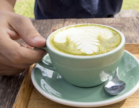 man holding a cup of hot green tea latte on wooden royalty free image