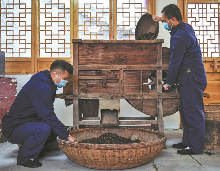 Two workers make black tea using a traditional method in a workshop in Xianyang, Shaanxi province
