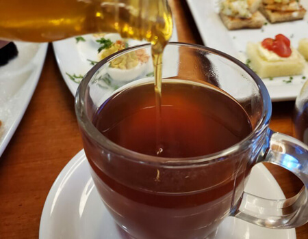 Honey being poured into a spiced peach tea, which came from the Heights tea shop, Tea Sip.