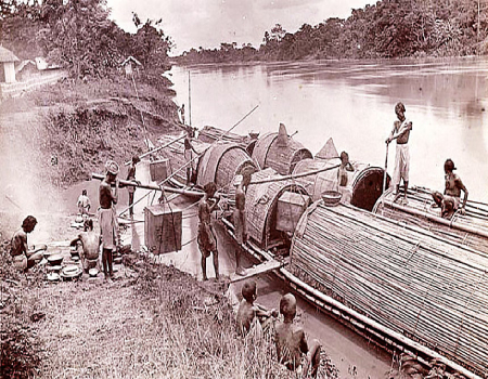 Bamboo boats were a common mode of transportation for tea, as illustrated in a 1903 photograph. The image captures workers loading tea boxes onto these boats. (Photo credit: Bourne and Shepherd Studio, Calcutta)